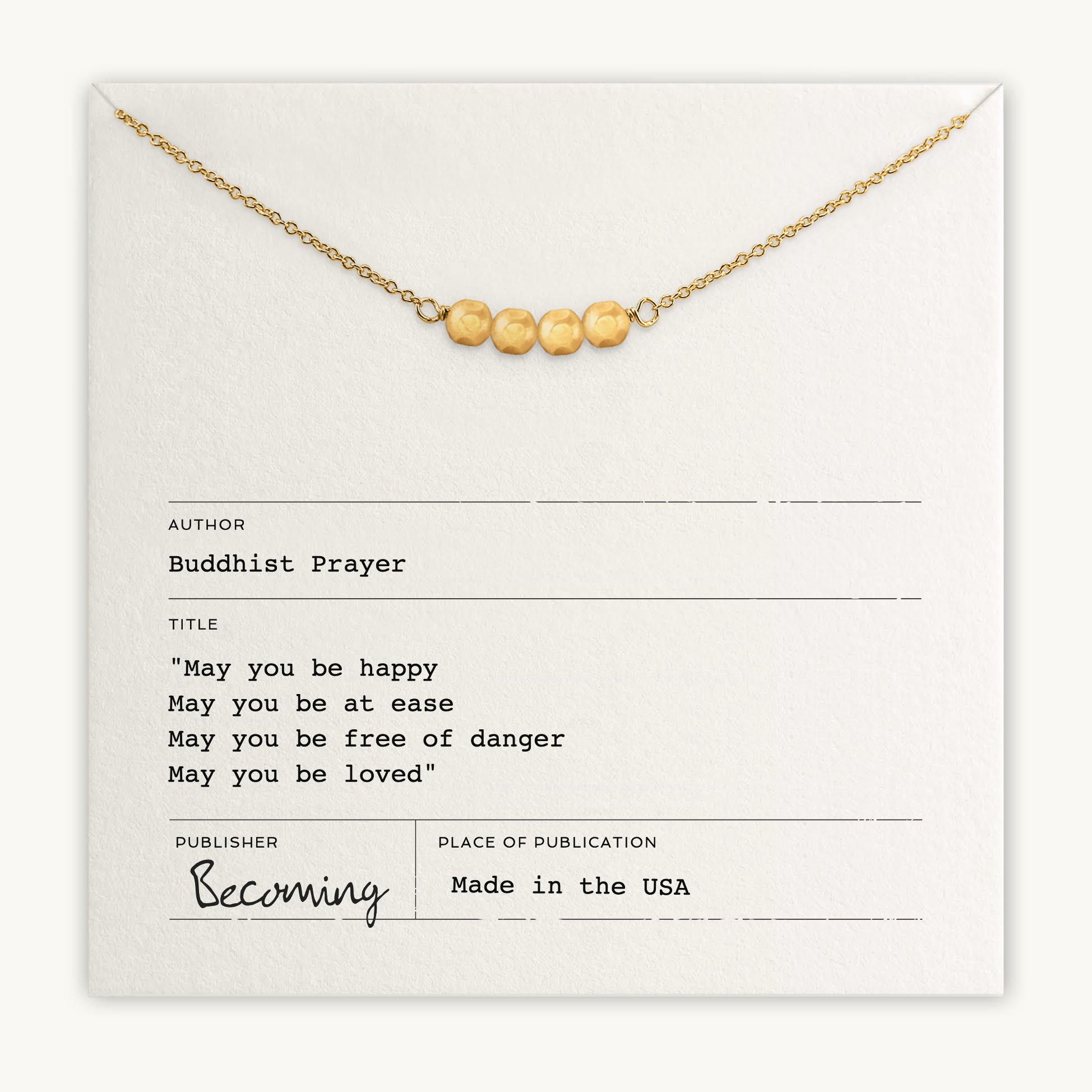 The May You Be Happy Necklace by Becoming Jewelry is a gold necklace with five beads on a card inscribed with a Buddhist prayer for happiness, health, safety, and love. Published in the USA.