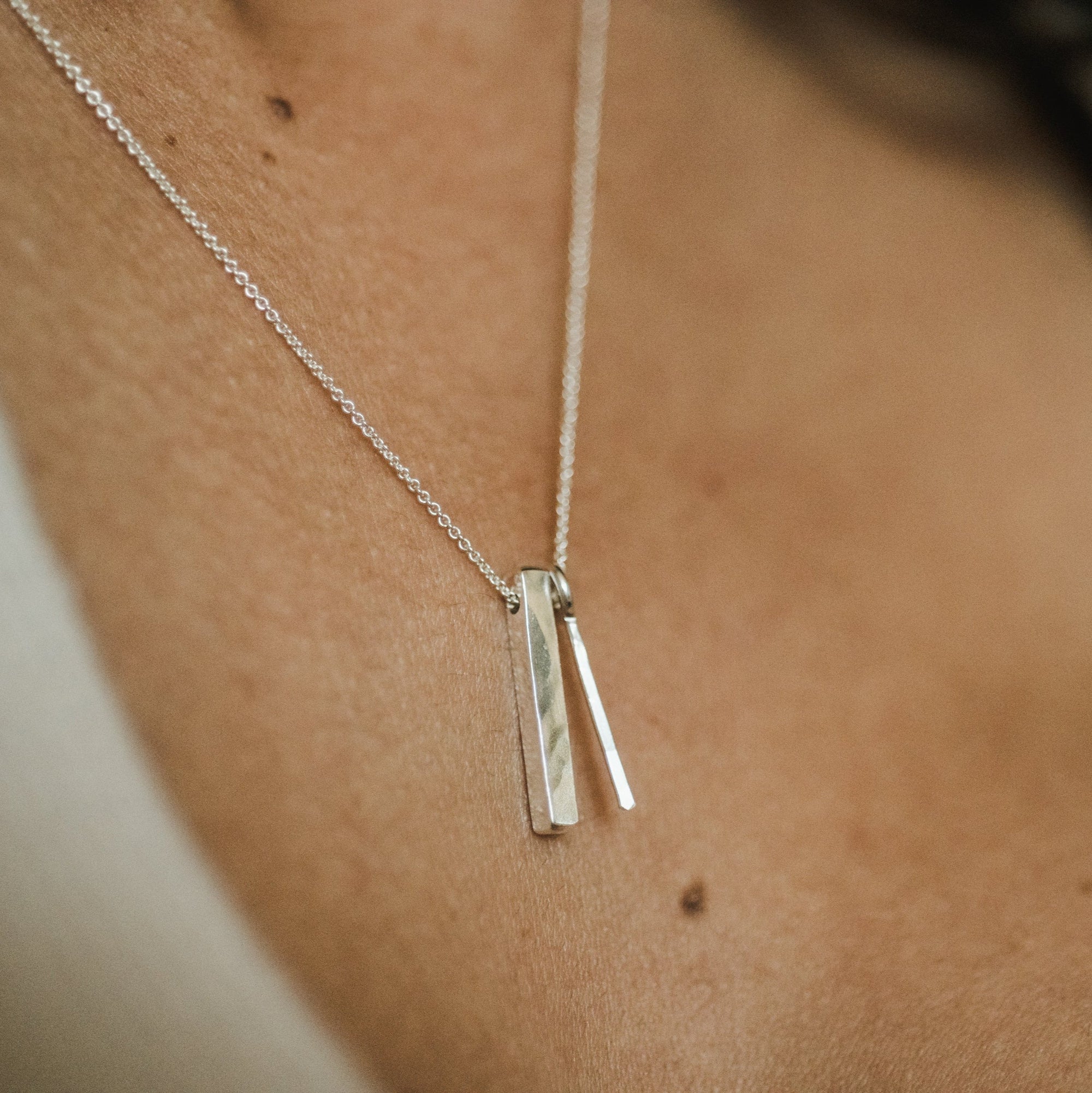 A close-up of a person&#39;s neck wearing the top-selling Through Thick &amp; Thin Necklace from Becoming Jewelry, adorned with two slim rectangular pendants.