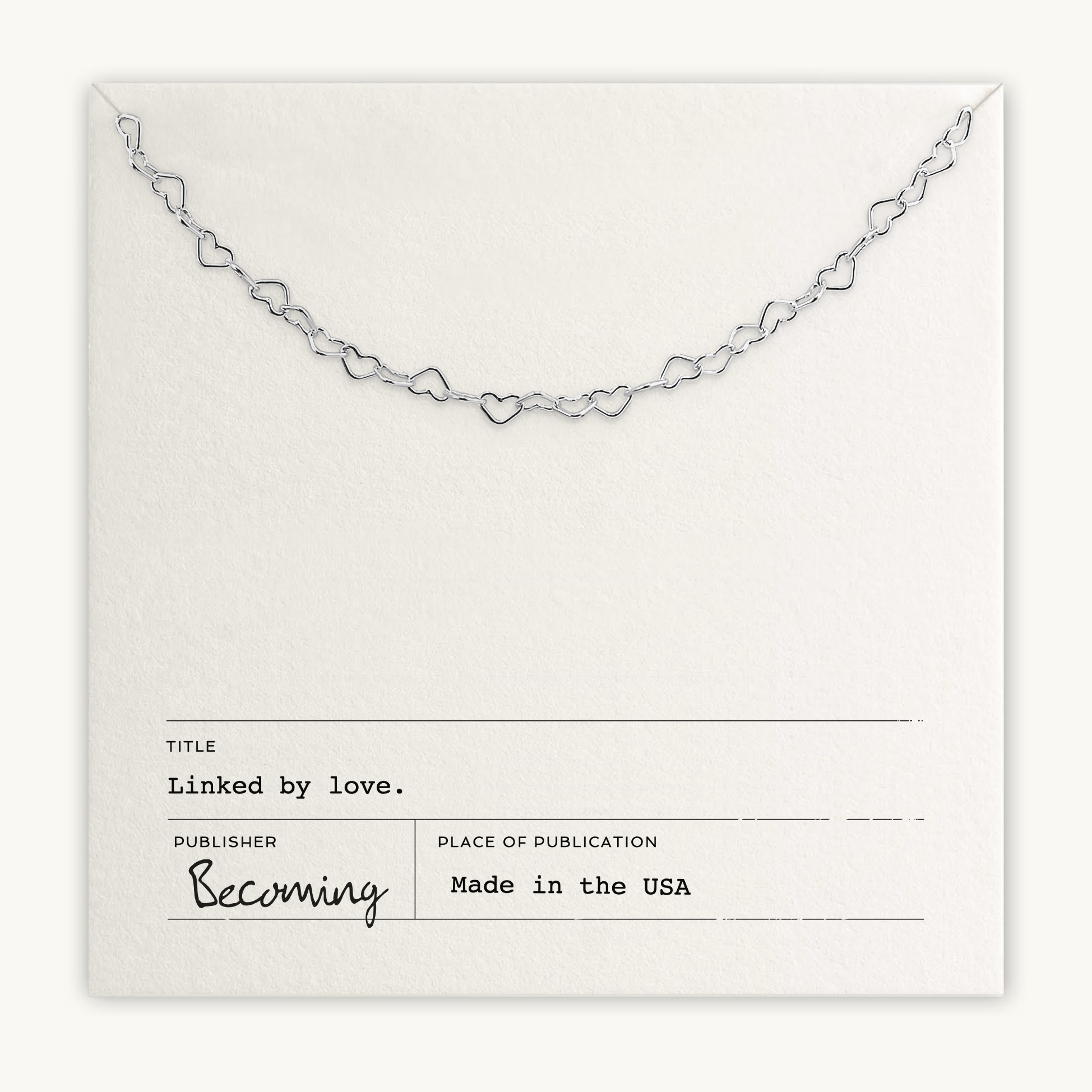 The Heart Chain Necklace from Becoming Jewelry, made in the USA, showcases intertwined hearts symbolizing a tender connection. It comes on a white card with "Linked by love," embodying cherished sentiments.