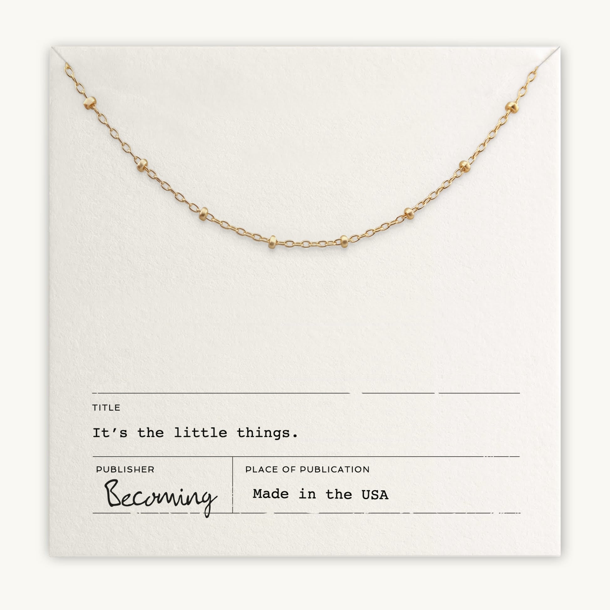 A delicate beaded chain necklace on a paper background is labeled: "Title: Little Things Necklace. Publisher: Becoming Jewelry. Place of publication: Made in the USA." This meaningful gift serves as a daily reminder of life's subtle joys.