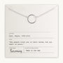 A Karma Necklace, featuring a simple silver circle pendant, is displayed on a paper card. The card includes an inspiring lesson by Wayne Dyer and information such as the author, title, and Becoming Jewelry as the publisher.