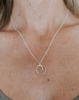 Close-up image of a person's neck wearing the Surrounded By Love Necklace by Becoming Jewelry, featuring two interlocking rings, serving as a meaningful reminder or perfect gift to someone special.