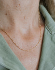 Close-up of a person wearing a thin gold chain, showcasing the Ups & Downs Necklace by Becoming Jewelry, paired perfectly with a light green collared shirt.